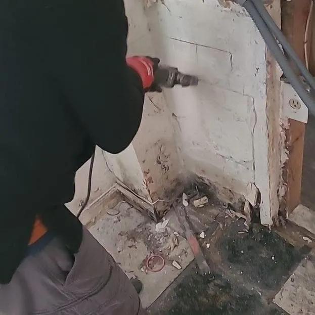 Technician removing wet wall material