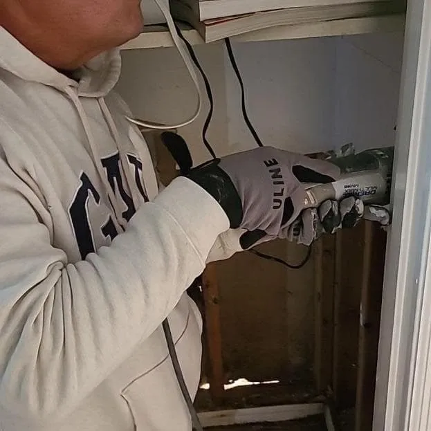 Technician cutting out damaged drywall