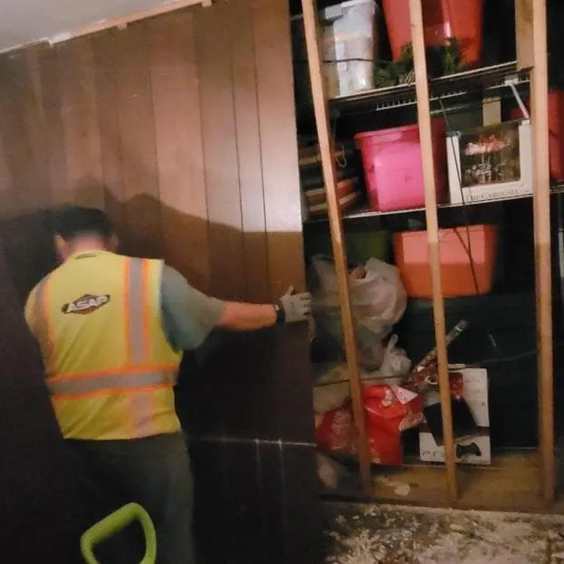 Technician removing wet wood paneling from a basement wall