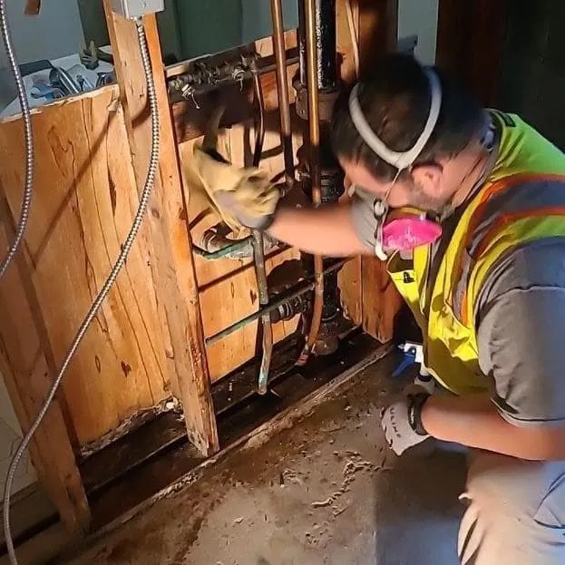 Technician wearing a respirator wiping down studs