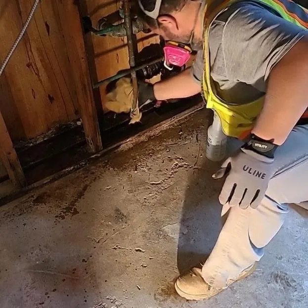 Technician working along the base of a wall