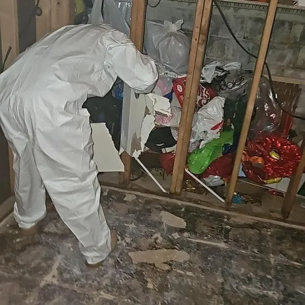 Technician in protective Tyvek suit working in a closet